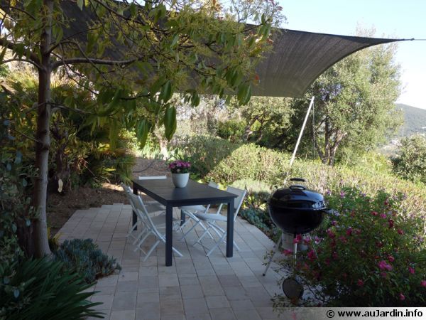 Une terrasse en pierres naturelles protégée par un voile d'ombrage